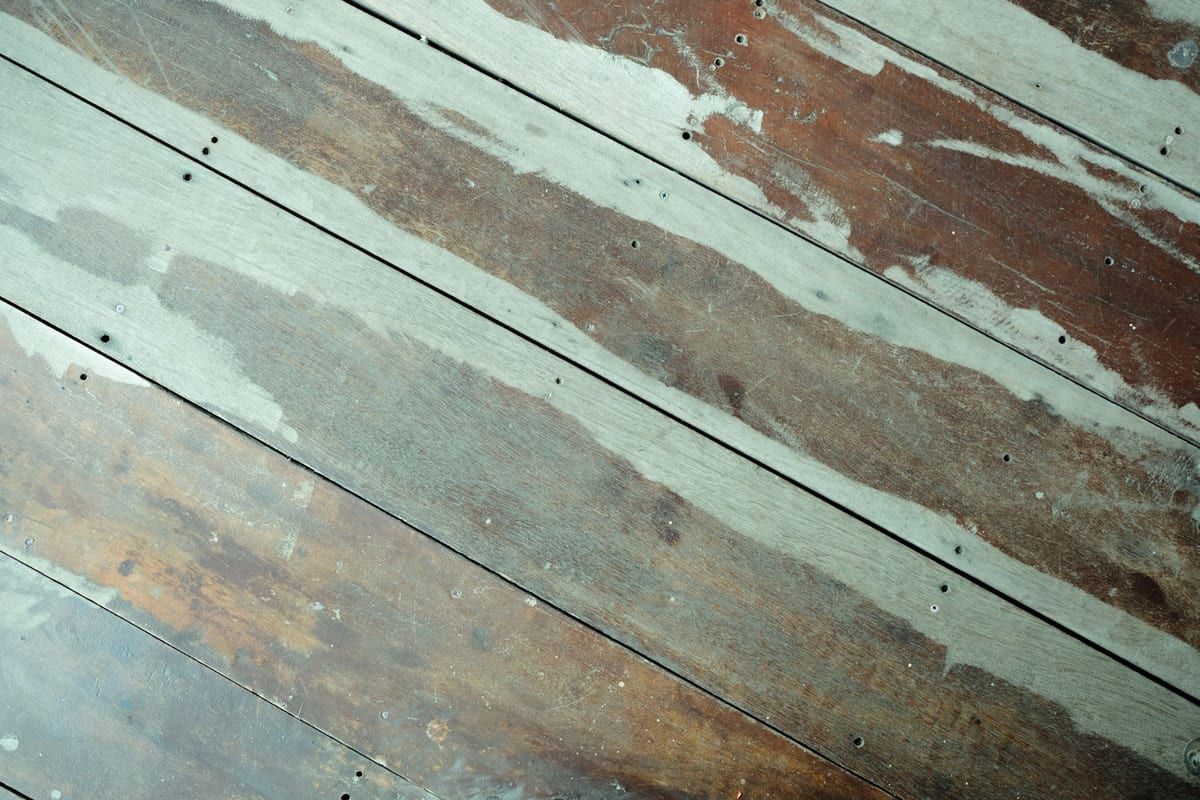 Old floorboards with worn, patchy varnish before work